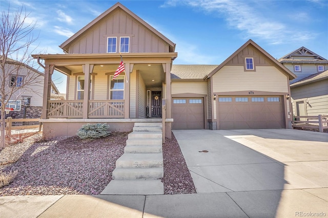 view of front facade featuring covered porch, board and batten siding, concrete driveway, and fence