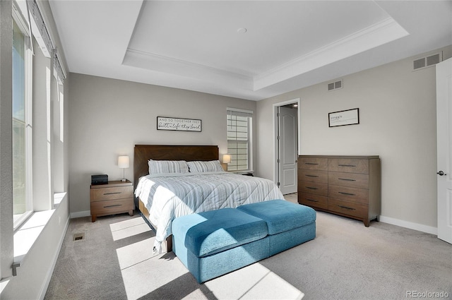 bedroom with a raised ceiling, visible vents, and light carpet