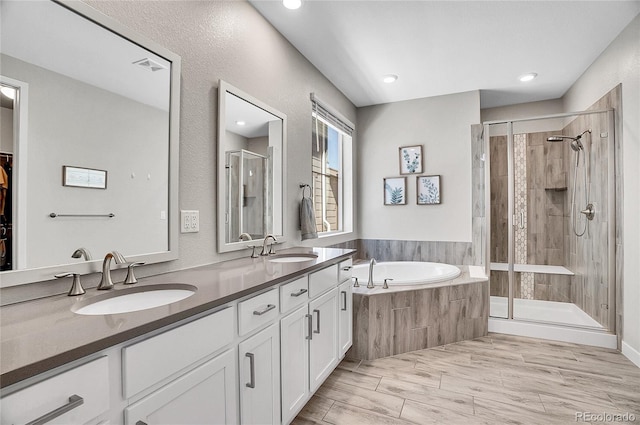 bathroom with a shower stall, a garden tub, double vanity, and a sink