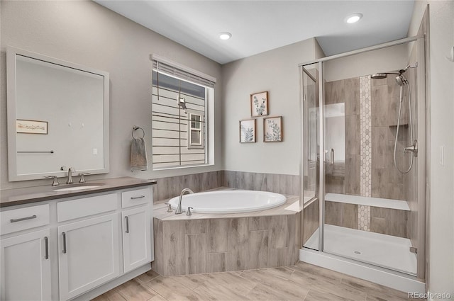 full bathroom with vanity, a garden tub, and a shower stall