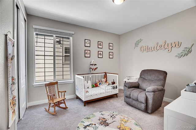 carpeted bedroom featuring a nursery area and baseboards