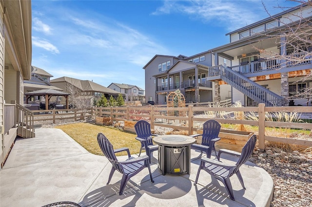 view of patio featuring a gazebo, fence, a residential view, and an outdoor fire pit