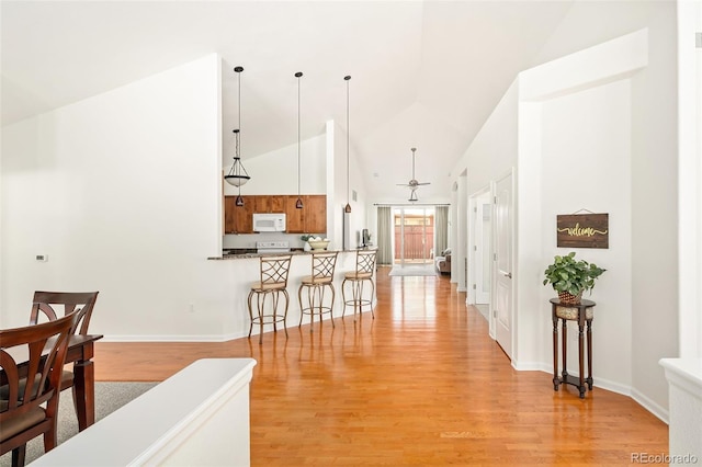 hall with high vaulted ceiling and light wood-type flooring