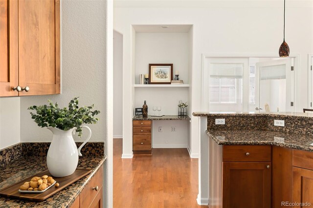 kitchen featuring dark stone counters, light hardwood / wood-style flooring, and pendant lighting