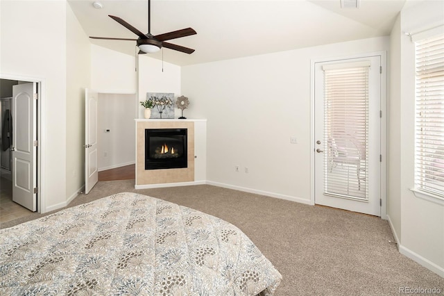 carpeted bedroom featuring a tiled fireplace, ceiling fan, multiple windows, access to exterior, and lofted ceiling