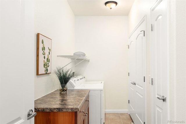 clothes washing area with washing machine and dryer, light tile patterned flooring, and cabinets