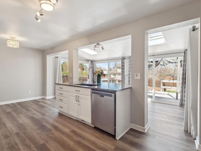 5945 W Morraine Ave, Littleton, CO 80128 - kitchen featuring stainless steel dishwasher, white cabinetry, wood finished floors, a sink, and baseboards