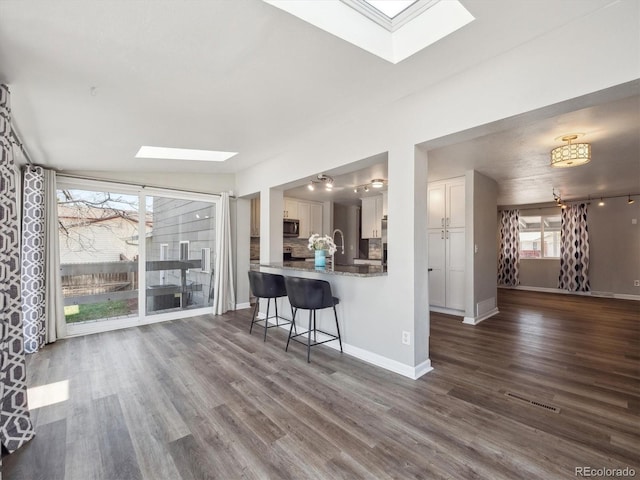 5945 W Morraine Ave, Littleton, CO 80128 - living room with dark wood-type flooring, visible vents, a skylight, and baseboards