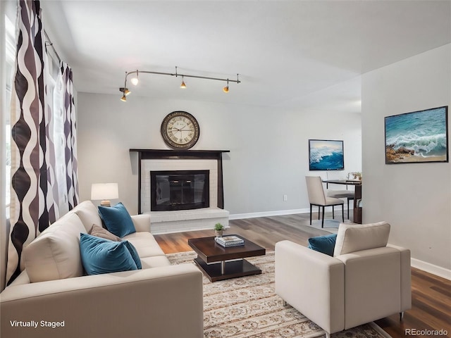 5945 W Morraine Ave, Littleton, CO 80128 - living area featuring baseboards, rail lighting, a glass covered fireplace, and wood finished floors