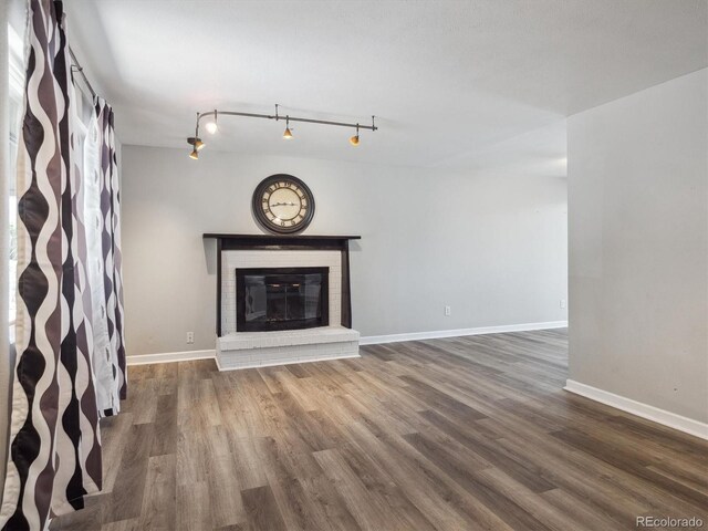 5945 W Morraine Ave, Littleton, CO 80128 - unfurnished living room featuring track lighting, wood finished floors, a fireplace, and baseboards