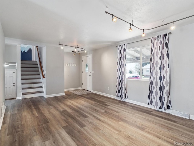 5945 W Morraine Ave, Littleton, CO 80128 - unfurnished living room with track lighting, wood finished floors, plenty of natural light, and stairs