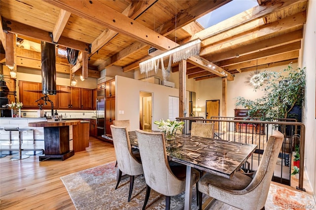 dining room featuring a skylight, beamed ceiling, wood ceiling, and light hardwood / wood-style floors