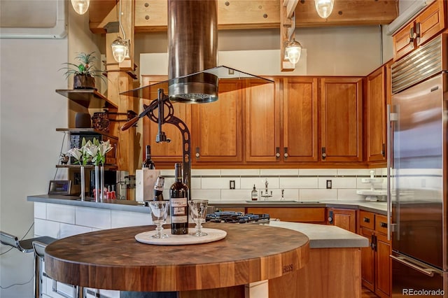 kitchen featuring a center island, sink, hanging light fixtures, built in refrigerator, and decorative backsplash