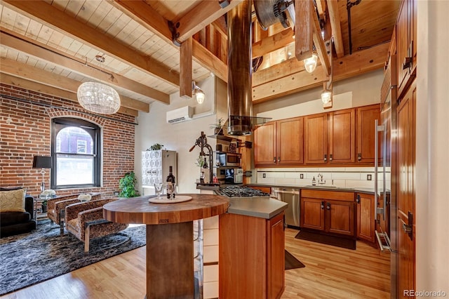 kitchen featuring brick wall, stainless steel appliances, a wall mounted AC, light hardwood / wood-style flooring, and hanging light fixtures