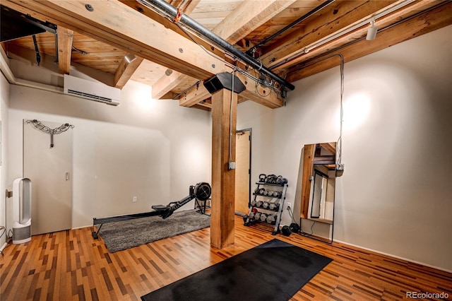 workout area with hardwood / wood-style flooring, a wall unit AC, and wood ceiling