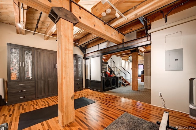 workout area with light wood-type flooring, electric panel, and wood ceiling