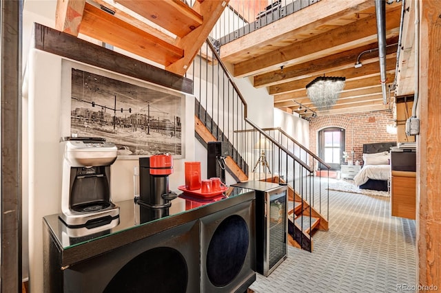 bar featuring carpet flooring, a notable chandelier, beam ceiling, and brick wall