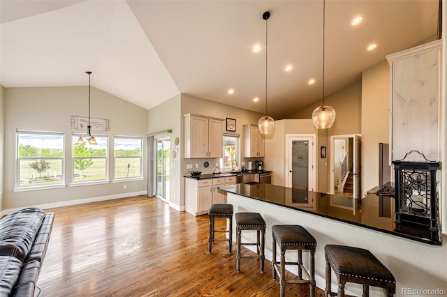 196 W 8th Ave, Byers, CO 80103 - kitchen featuring dark countertops, wood finished floors, a peninsula, light brown cabinets, and baseboards