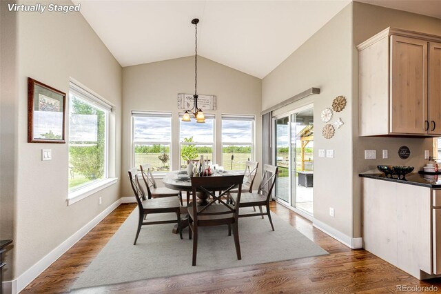 196 W 8th Ave, Byers, CO 80103 - dining area with a chandelier, dark wood-style flooring, vaulted ceiling, and baseboards