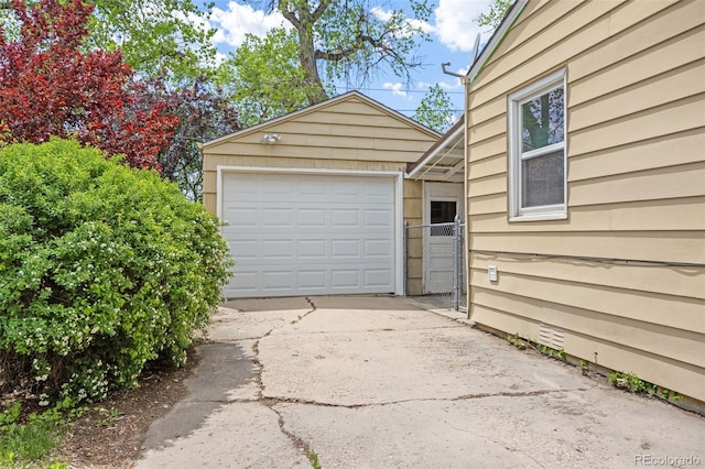 detached garage with driveway and a gate