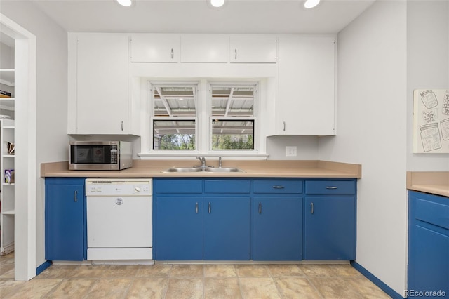 kitchen with stainless steel microwave, a sink, white dishwasher, blue cabinetry, and light countertops