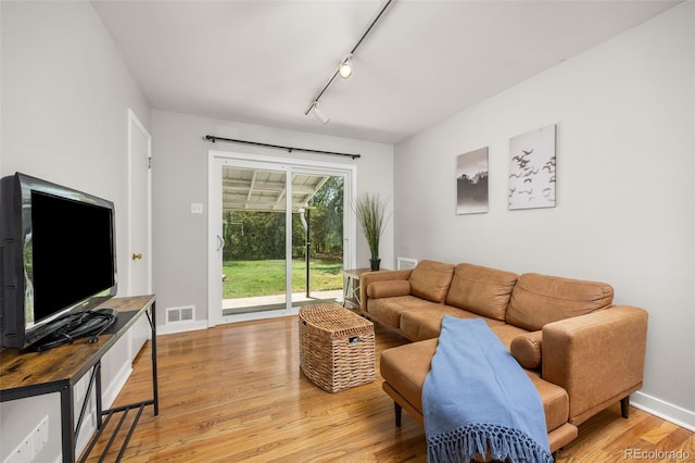 living room with track lighting, light wood-type flooring, and baseboards