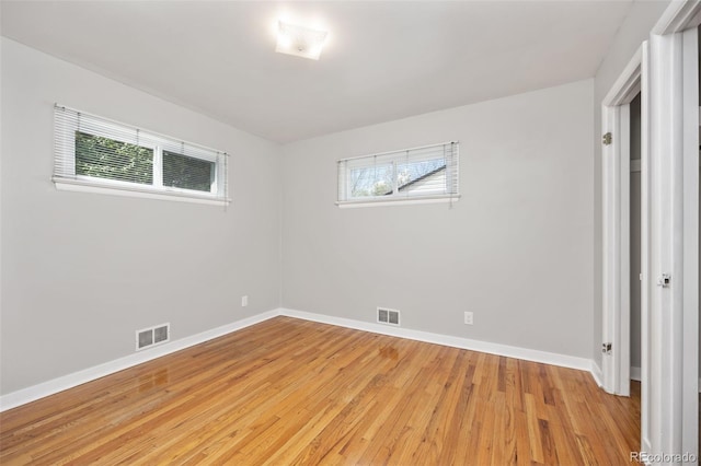 unfurnished bedroom with multiple windows, light wood-style flooring, and baseboards