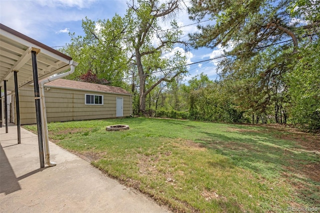 view of grassy yard with a fire pit and a patio
