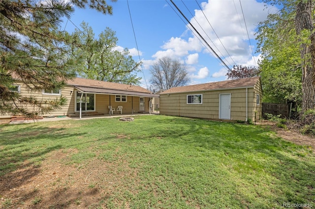 back of house featuring a patio area, a fire pit, and an outbuilding