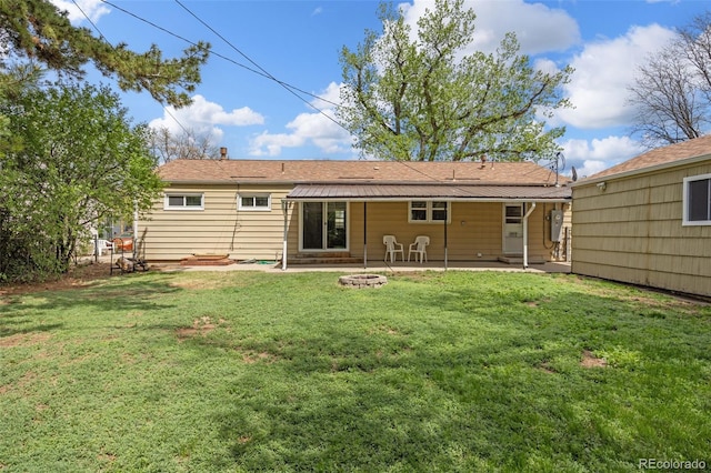 back of property with a patio area, a lawn, a fire pit, and roof with shingles