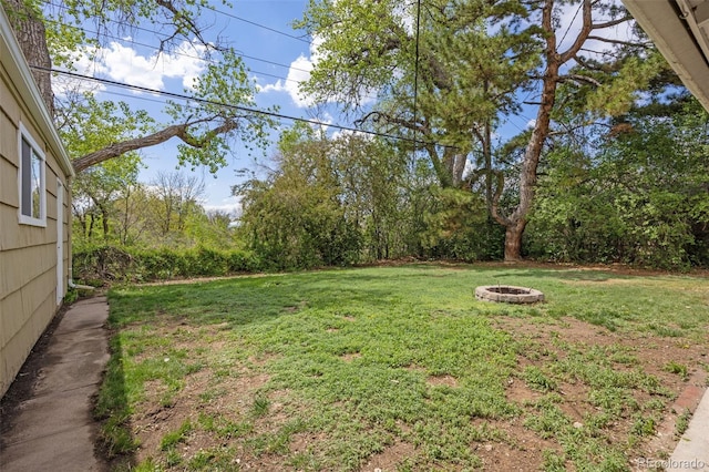 view of green lawn with a fire pit