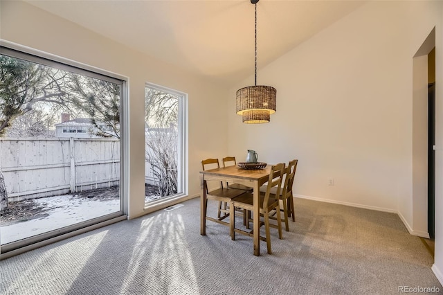 carpeted dining space featuring vaulted ceiling