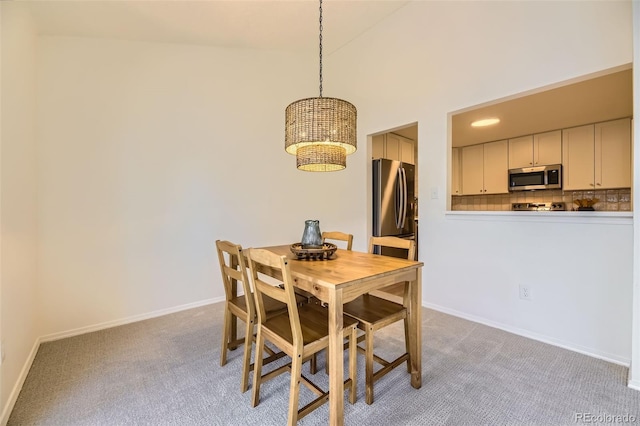 dining room featuring high vaulted ceiling and light carpet