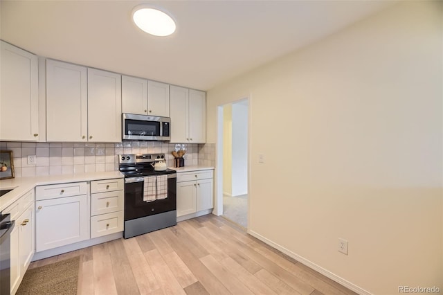 kitchen with white cabinets, stainless steel appliances, light wood-type flooring, and tasteful backsplash