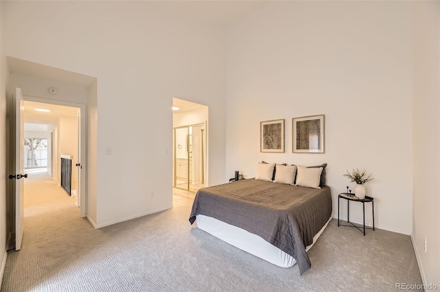 carpeted bedroom featuring a high ceiling and ensuite bath