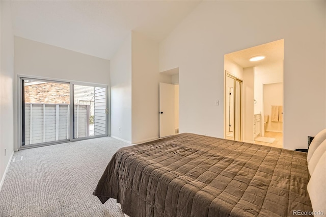 bedroom featuring ensuite bathroom, high vaulted ceiling, and dark colored carpet