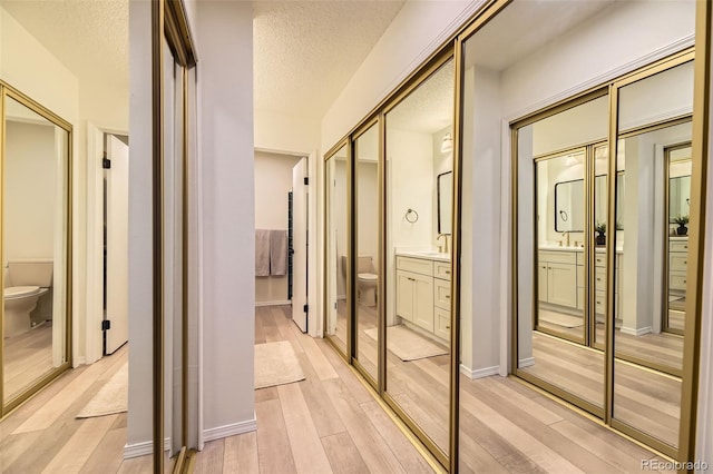 corridor featuring a textured ceiling and light hardwood / wood-style floors