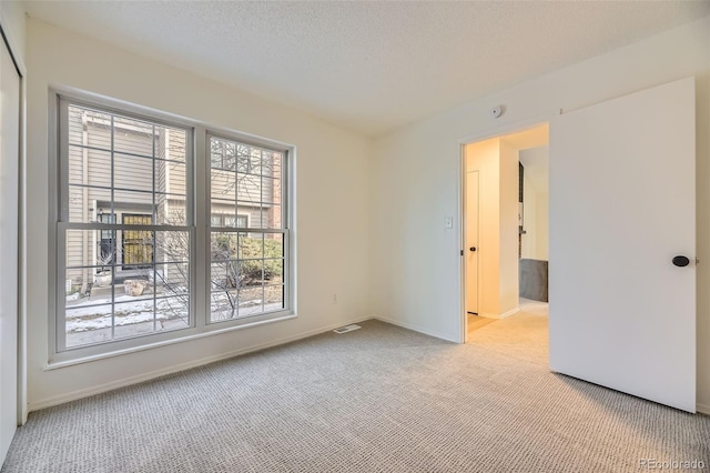 unfurnished room with a textured ceiling and light carpet