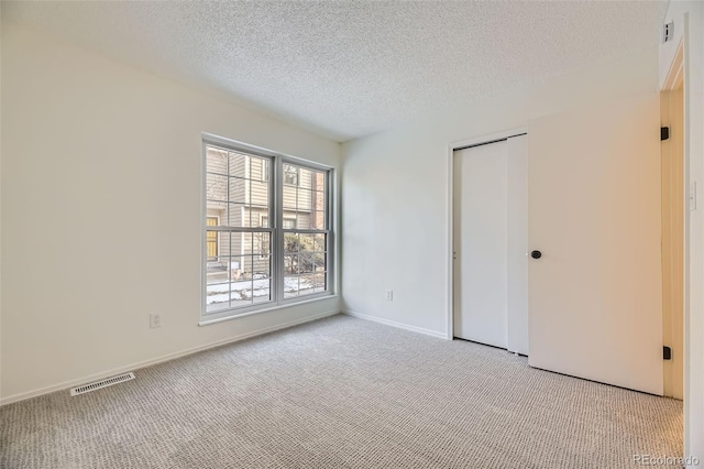 carpeted empty room featuring a textured ceiling