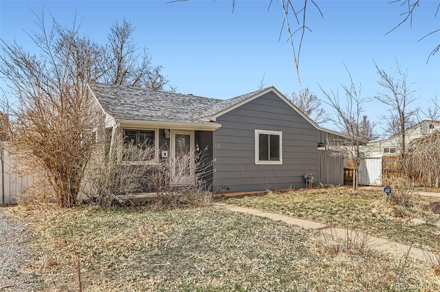 view of side of property with fence and a shingled roof