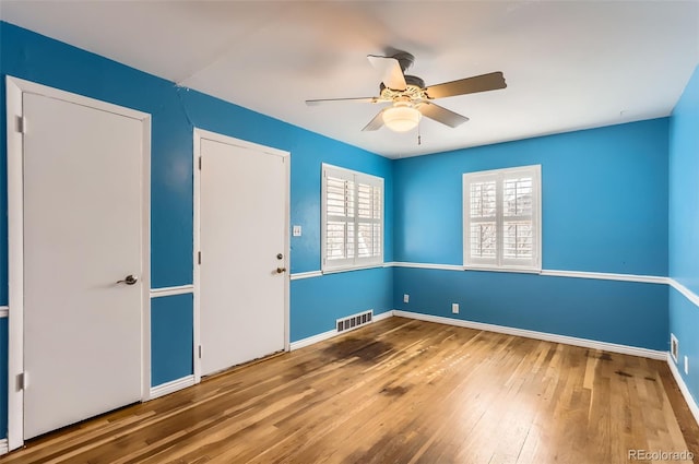 unfurnished room featuring visible vents, baseboards, a ceiling fan, and wood-type flooring