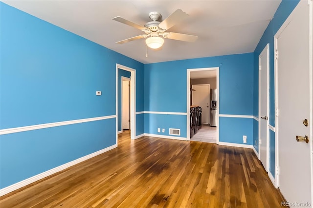 unfurnished bedroom with a ceiling fan, visible vents, wood finished floors, and baseboards