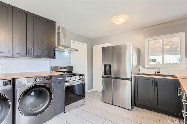 kitchen featuring wall chimney range hood, light countertops, independent washer and dryer, stainless steel appliances, and a sink