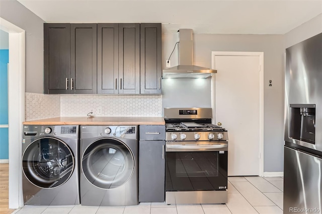 laundry area with washing machine and clothes dryer, laundry area, baseboards, and light tile patterned floors