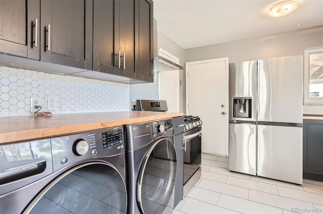 clothes washing area with washer and dryer and light tile patterned floors