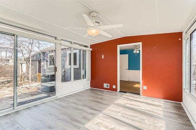 empty room featuring a wealth of natural light, wood finished floors, a ceiling fan, and vaulted ceiling