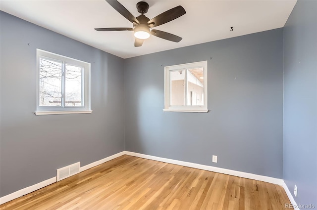 empty room featuring visible vents, a healthy amount of sunlight, baseboards, and wood finished floors