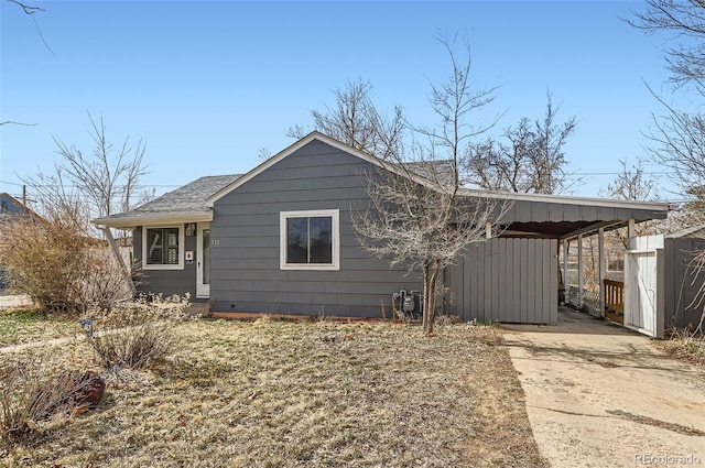 view of home's exterior with driveway, a shingled roof, and an attached carport
