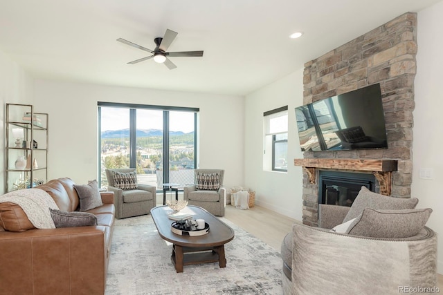 living room with hardwood / wood-style flooring, ceiling fan, and a fireplace