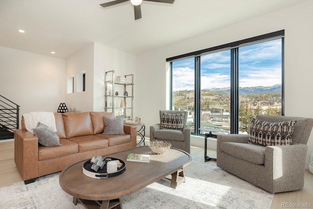 living room featuring a mountain view, ceiling fan, and light hardwood / wood-style flooring